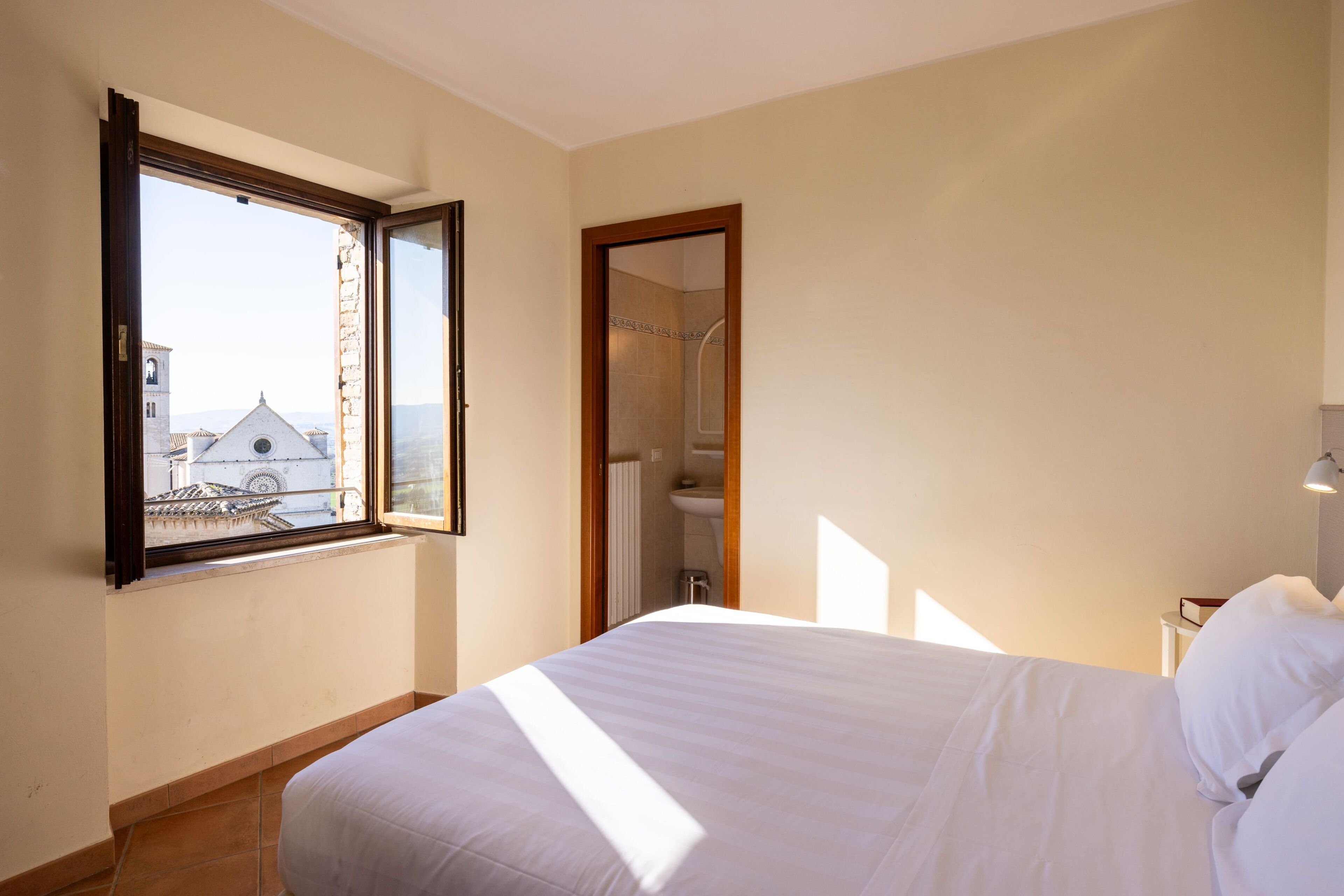Un dormitorio con una cama, una ventana y vista a un edificio.