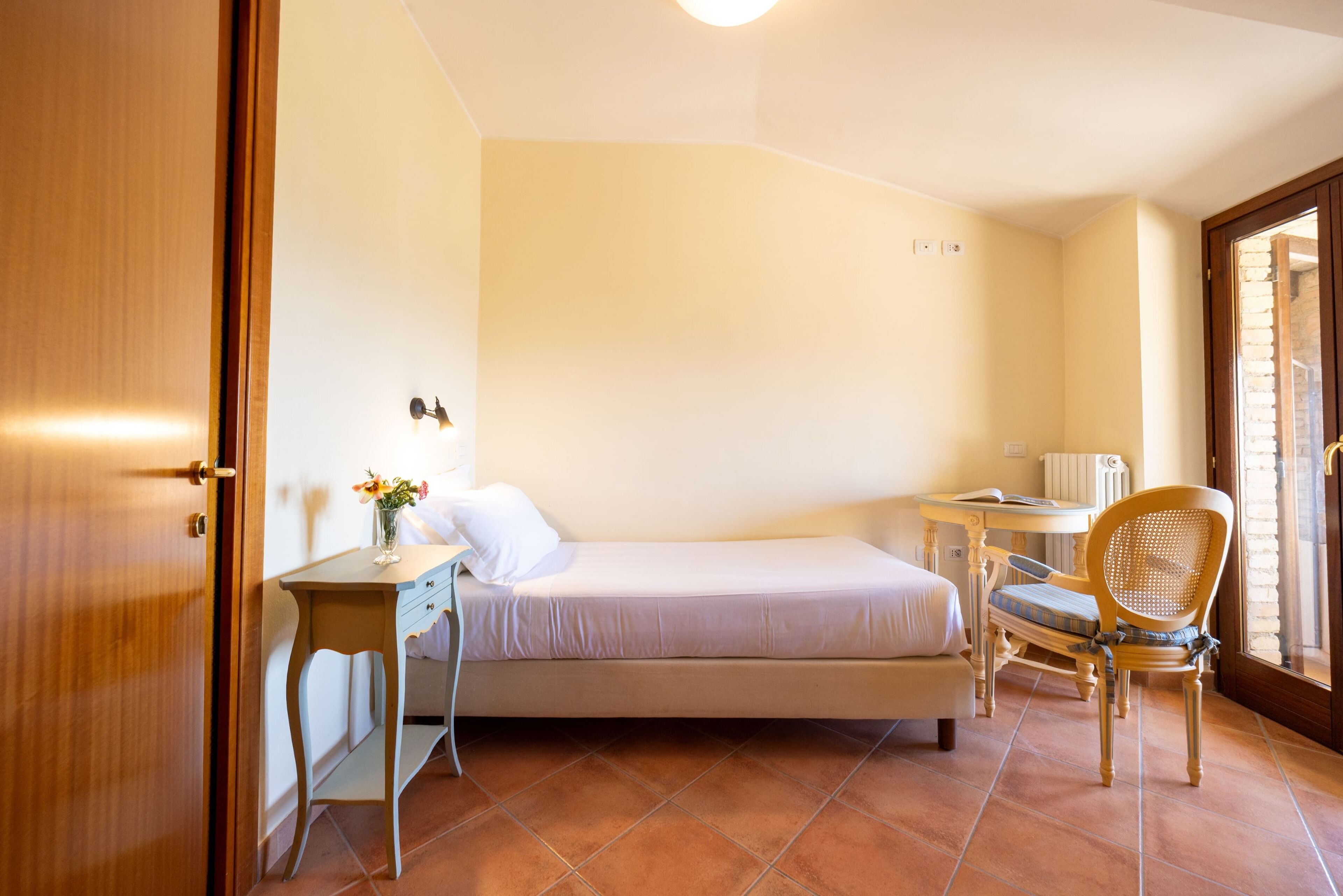 Un dormitorio pequeño y ordenado con una cama individual, un escritorio y una silla.