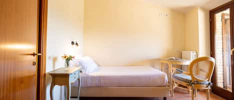 Un dormitorio pequeño y ordenado con una cama individual, un escritorio y una silla.