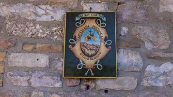 Una placa con la inscripción "CARITAS CLARITAS" y "MISIONERO FRANCISCANO" en una pared de ladrillo.