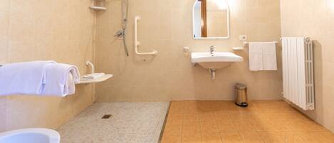 A bathroom with a toilet, sink, shower, and handrails.
