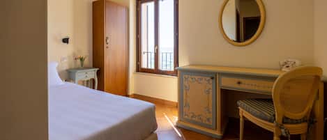 A bedroom with a bed, a dresser, a chair, a mirror, and a window with a view.