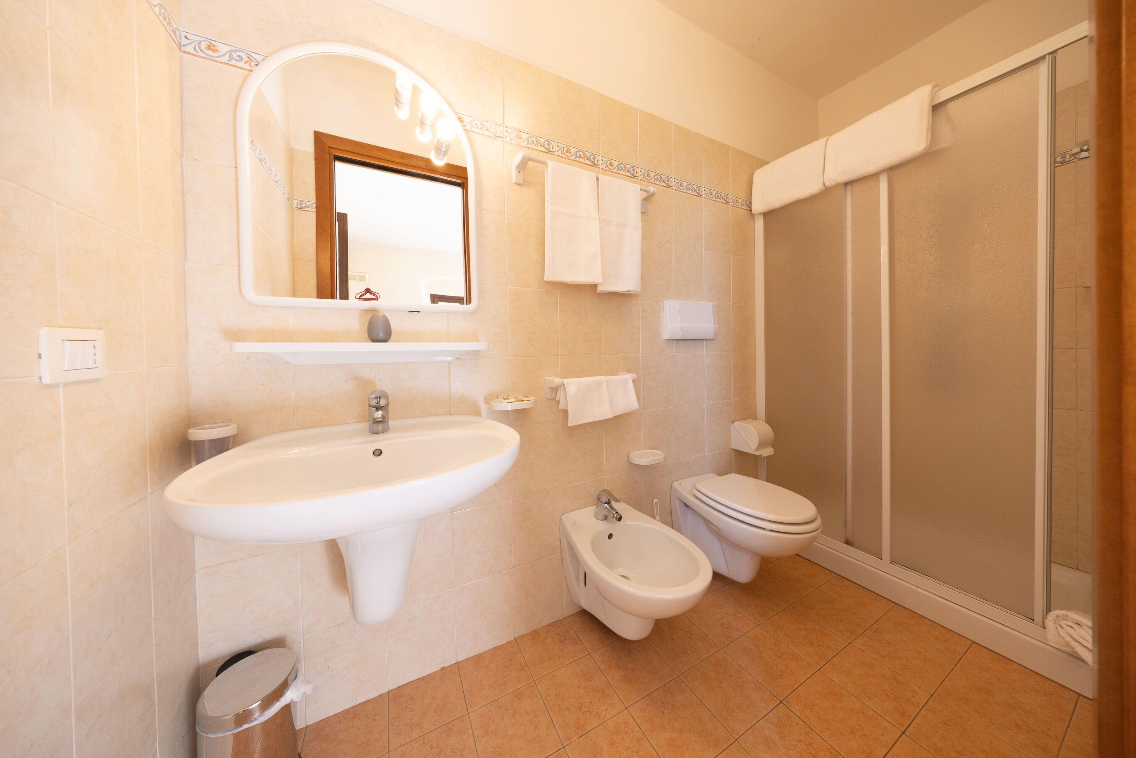A bathroom with a sink, bidet, toilet, and a shower enclosure.