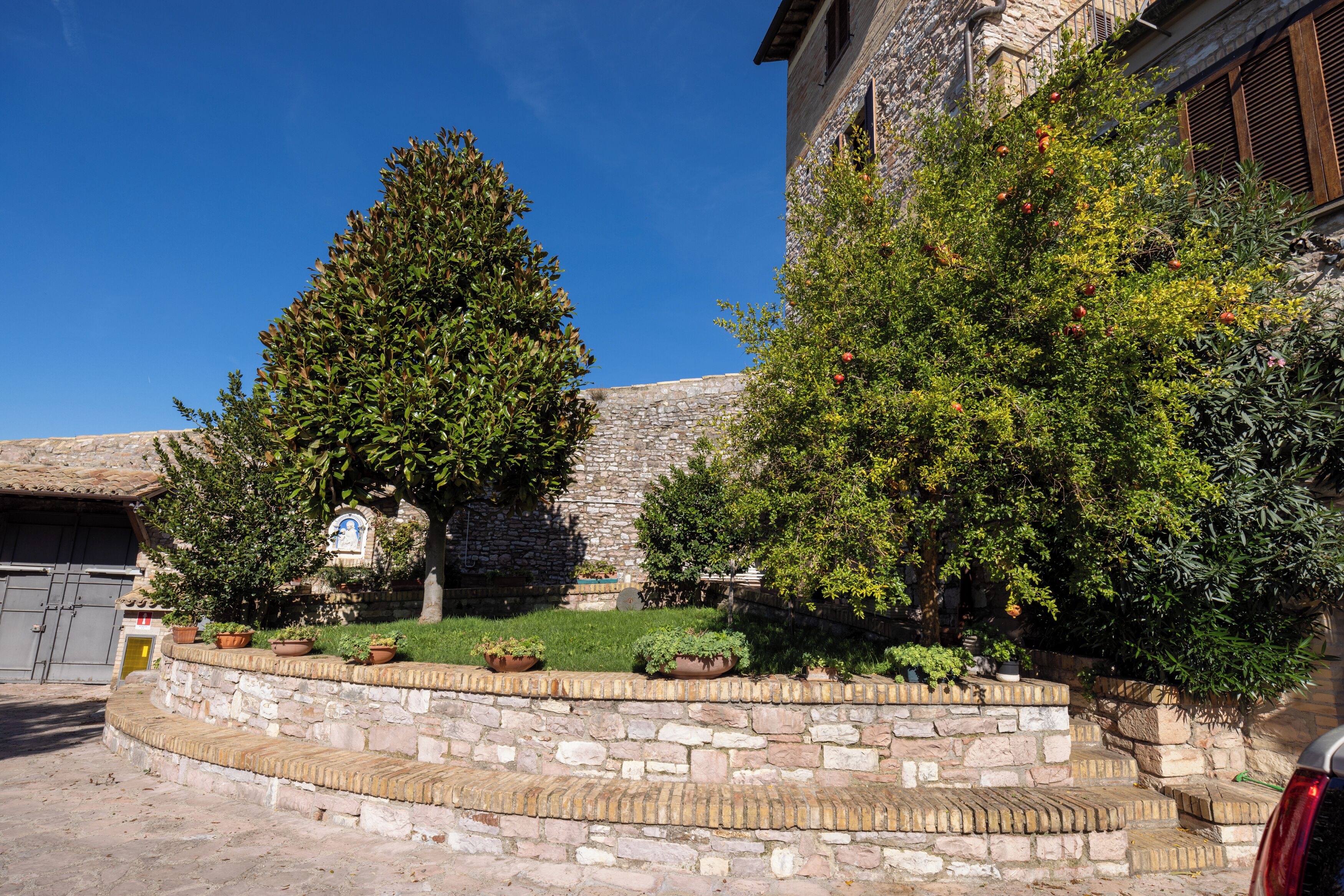 A stone staircase leading to a building with a stone wall and potted plants.