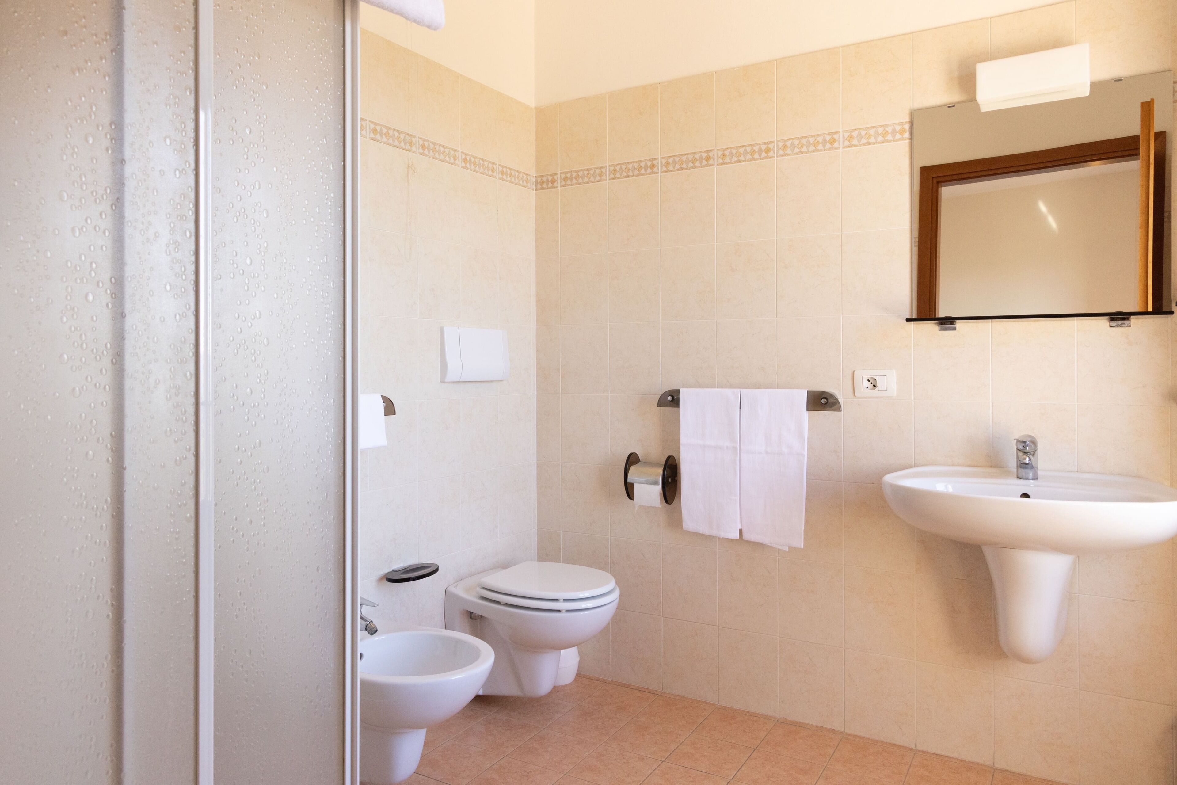Ein Badezimmer mit zwei Toiletten, einem Waschbecken und einem Spiegel.