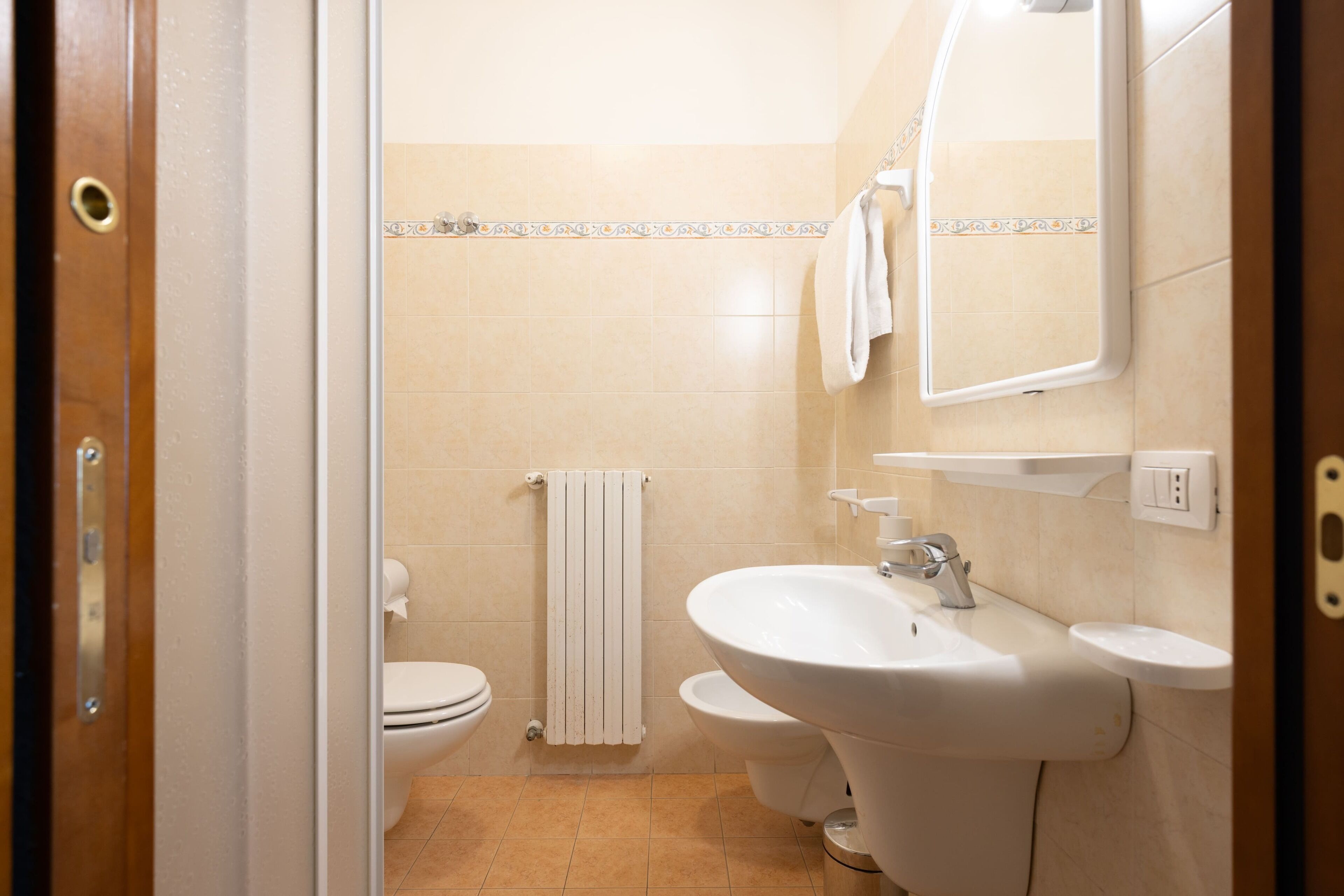 A bathroom with a toilet, sink, and mirror.