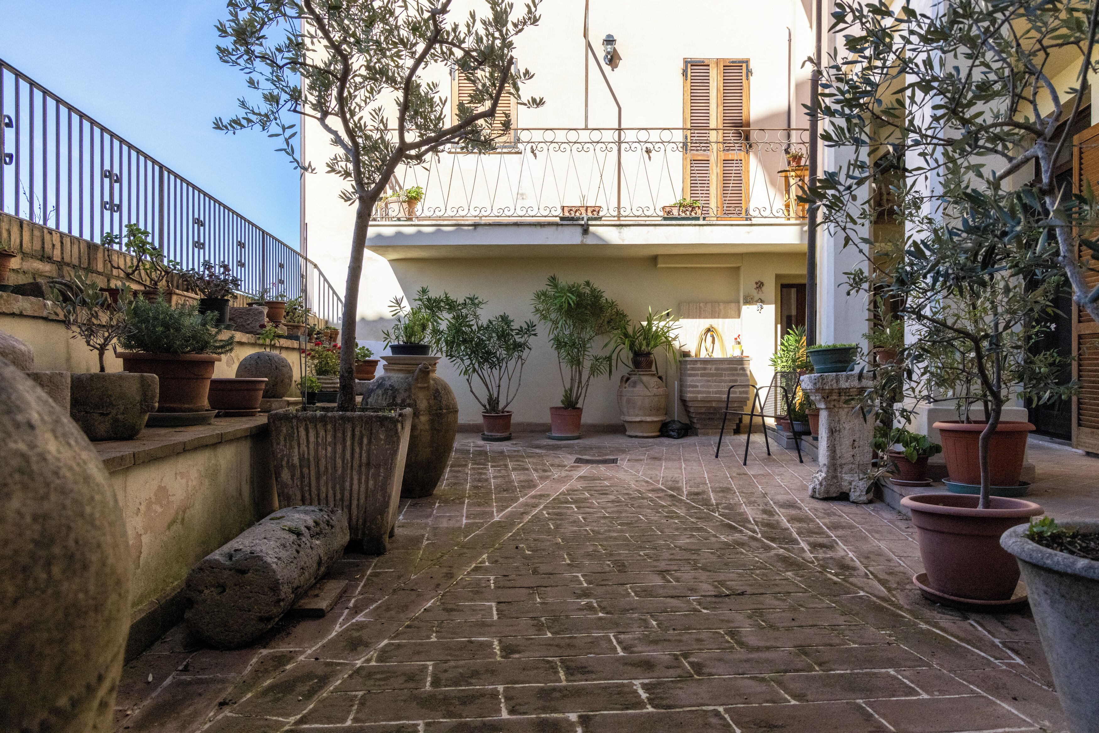Un patio con plantas en macetas, paredes de piedra y suelo de ladrillo.