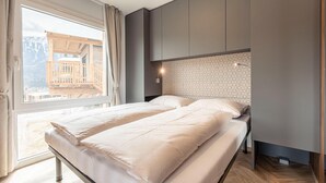 A bedroom with a large window, a bed, and a wardrobe. - Beautiful tree house in the Gailtal valley (Kötschach-Mauthen)