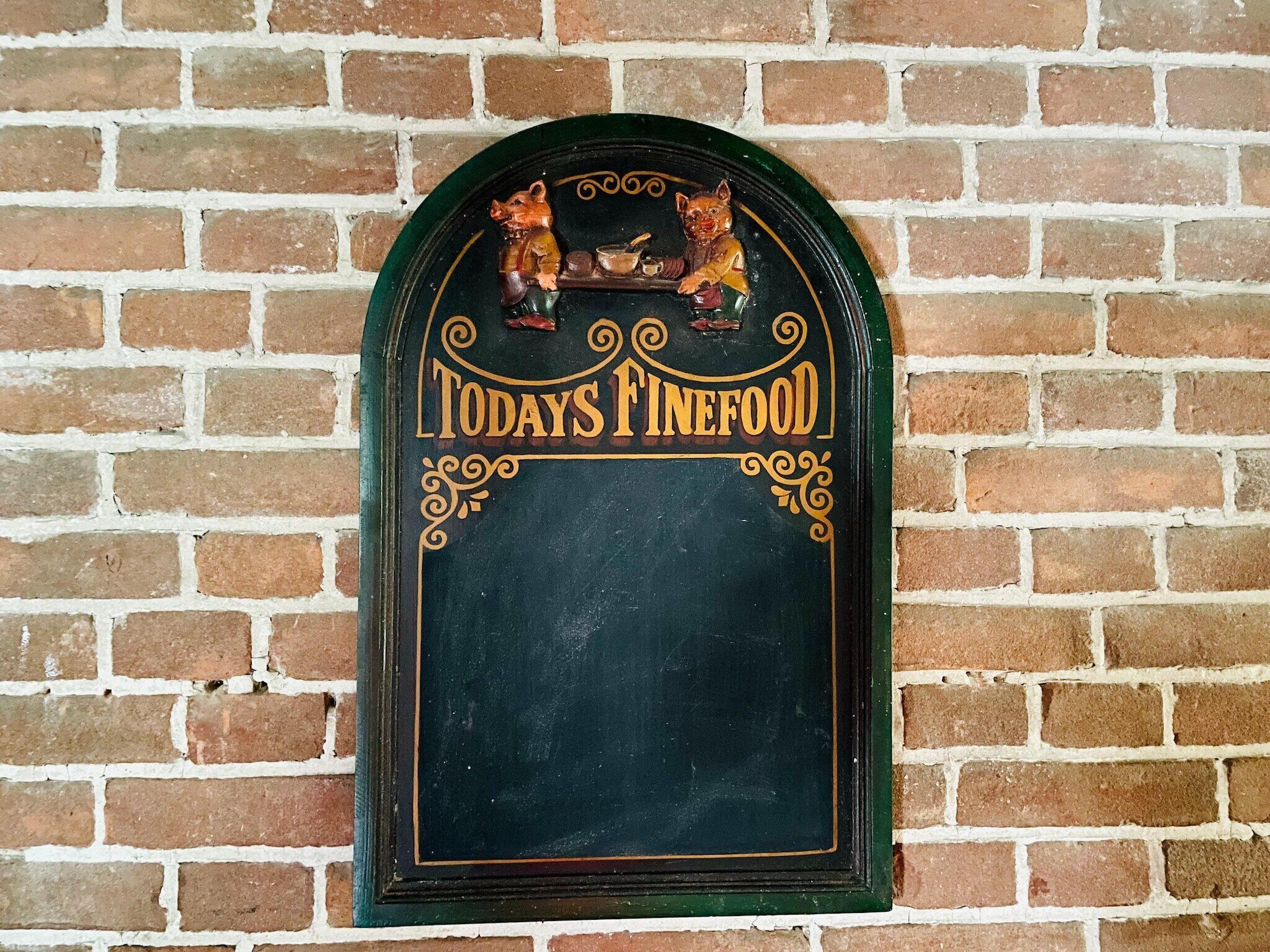 A chalkboard sign with "TODAY'S FINEFOOD" written on it, mounted on a brick wall.