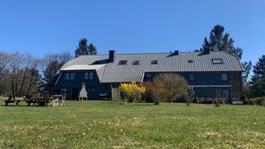A large building with a tiled roof, a front entrance, and a grassy area with picnic tables.
