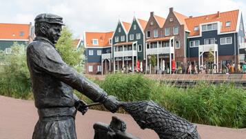 Eine Statue eines Mannes, der einen Fisch aus einem Baumstamm zieht, mit traditionellen Gebäuden im Hintergrund.