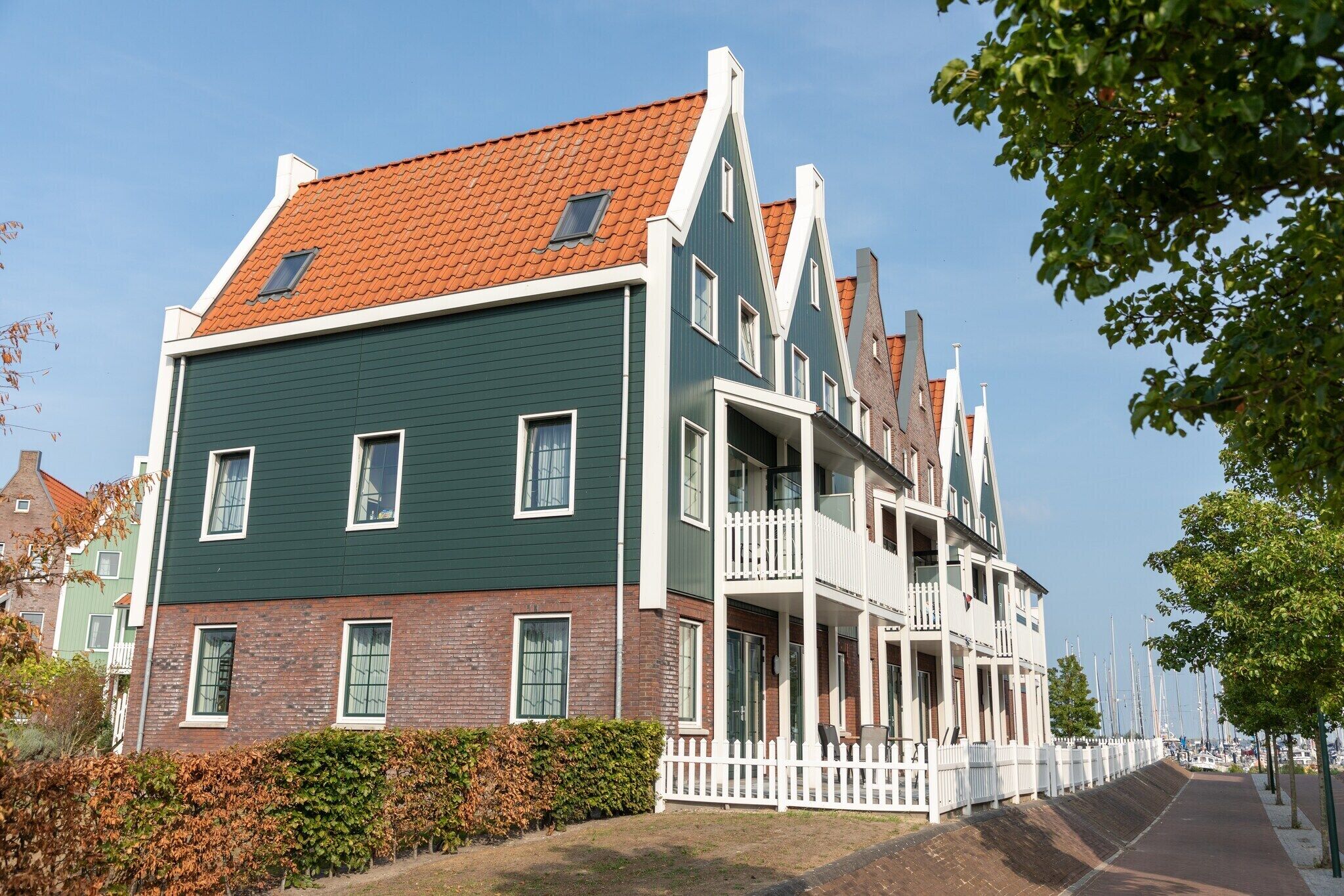 Ein traditionelles niederländisches Gebäude mit grüner Fassade, weißer Verzierung und einem roten Ziegeldach.