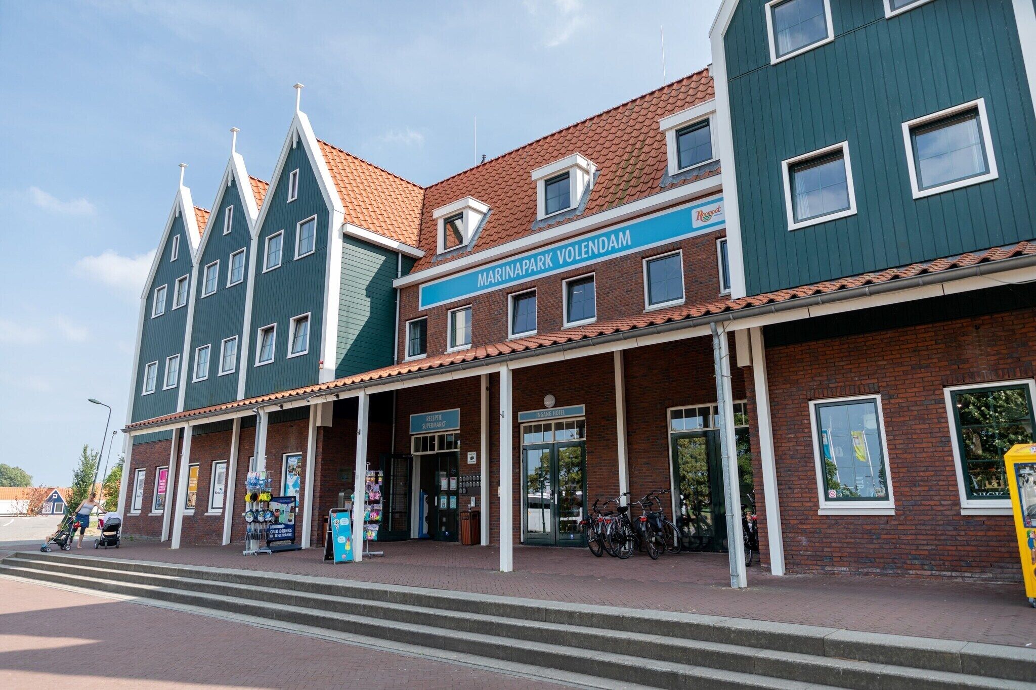 Um edifício com uma placa que diz “MARINAPARK VOLENDAM” e uma entrada coberta.