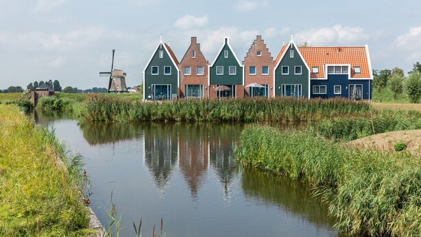 A row of traditional Dutch houses by a canal with a windmill in the background. - Stylish Stay in Volendam (Volendam)