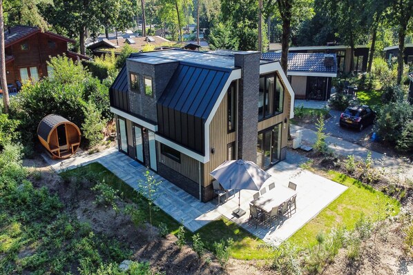 Une maison moderne avec un toit en pente, de grandes fenêtres et un espace patio.