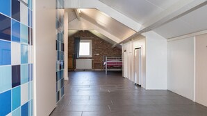 Un couloir avec un mur carrelé, un lit superposé et un radiateur.