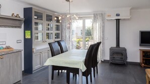 Un coin repas avec une table dressée pour quatre personnes, une cuisinière encastrée et un téléviseur posé sur un meuble.