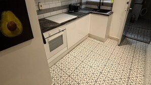 Una cocina moderna con armarios blancos, suelo de baldosas estampadas y una ventana que proporciona luz natural.