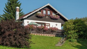 Une maison avec un toit en pente, une cheminée en briques et une clôture en bois.