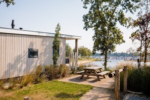 Eine Holzhütte mit Picknicktisch und Blick auf einen See und einen Hafen.