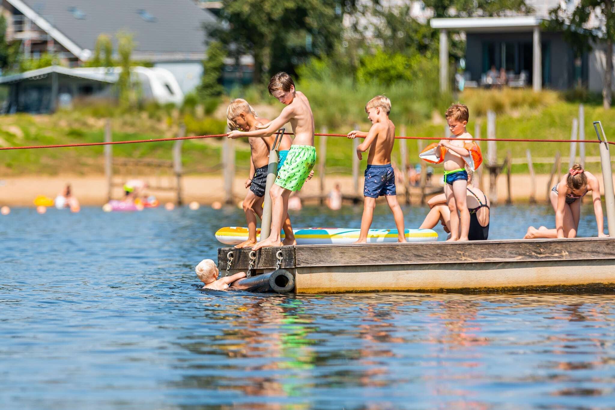 En träbrygga med människor som står på den, några håller i surfbrädor.