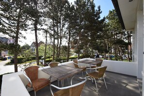 Guests can enjoy seating on the furnished outdoor terrace surrounded by tall trees.