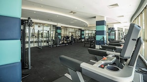 A modern gym with various exercise equipment, including weight machines and cardio machines, and large windows allowing natural light. - Cozy 2-bedroom apartment with AC, fitness room, WiFi in phenomenal Antalya (Antalya)