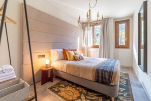Une chambre à coucher avec un lit, une table de chevet, une lampe et une fenêtre avec des rideaux.