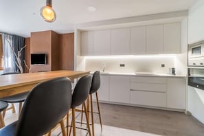 A modern kitchen with white cabinets, a wooden dining table, and black chairs. - Stone Home in Benasque near Scenic Lake (Benasque)