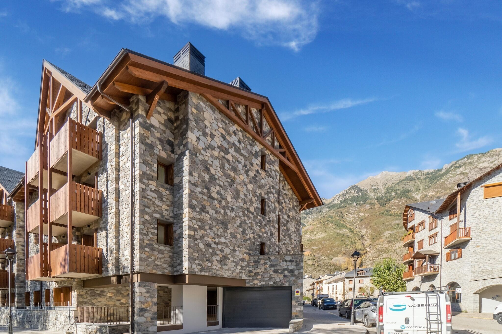A multi-story building with stone facade and wooden balconies, located in a mountainous area with clear skies.