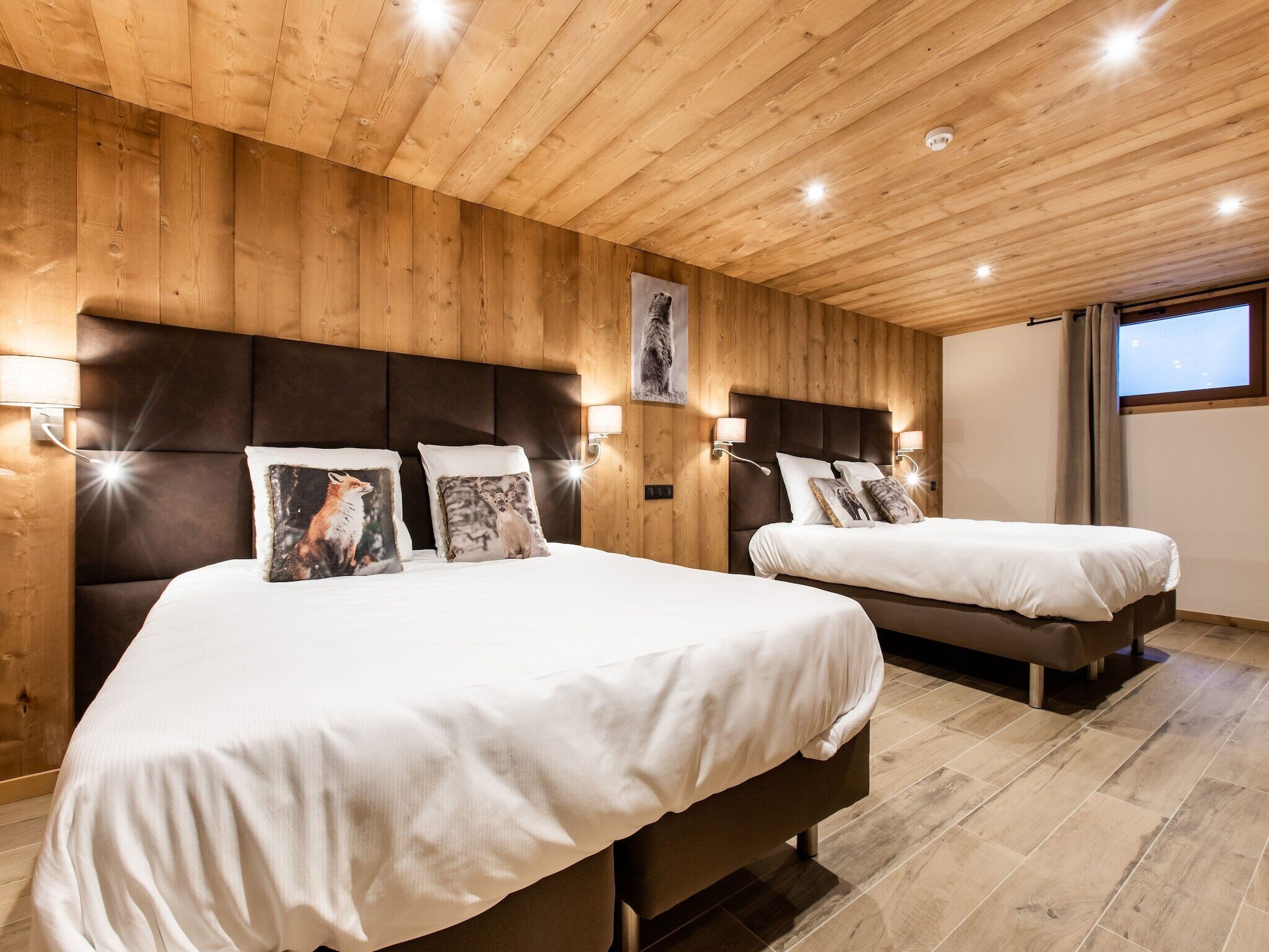 Une chambre d’hôtel avec deux lits, des murs lambrissés et une grande fenêtre.