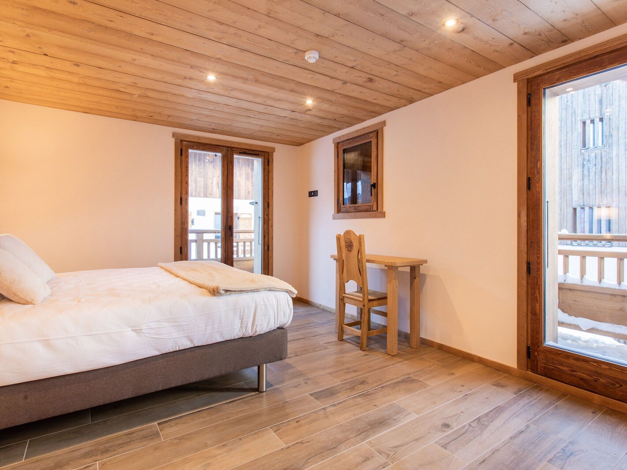 Quarto com cama, escrivaninha de madeira e uma cadeira.