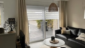 A modern living room with a black leather sofa, a round coffee table, and a large sliding glass door leading to a balcony. - Modern house in Jalhay with terrace (Jalhay)