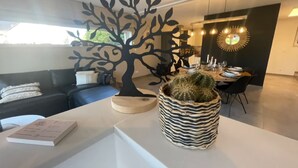 A modern living room with a black tree-shaped decoration, a cactus in a zebra-striped pot, and a dining area with a round mirror and pendant lights. - Modern house in Jalhay with terrace (Jalhay)