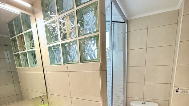 Ein modernes Badezimmer mit Waschbecken, Spiegel und Toilette in Weiß.