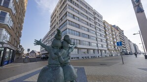 Una estatua de dos figuras abrazándose en una acera urbana.