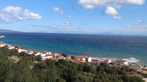 A coastal town with buildings along the shoreline, a clear sky, and a view of the sea. - Naiad Studio Sea View (Poros)
