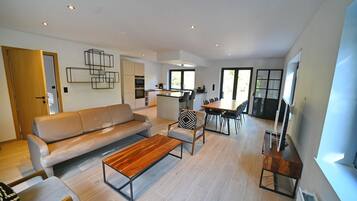 A modern living room with a sofa, coffee table, and dining area.