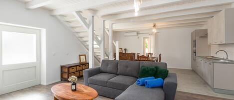 A spacious living area with a gray sectional sofa, a wooden coffee table, and a kitchen in the background.