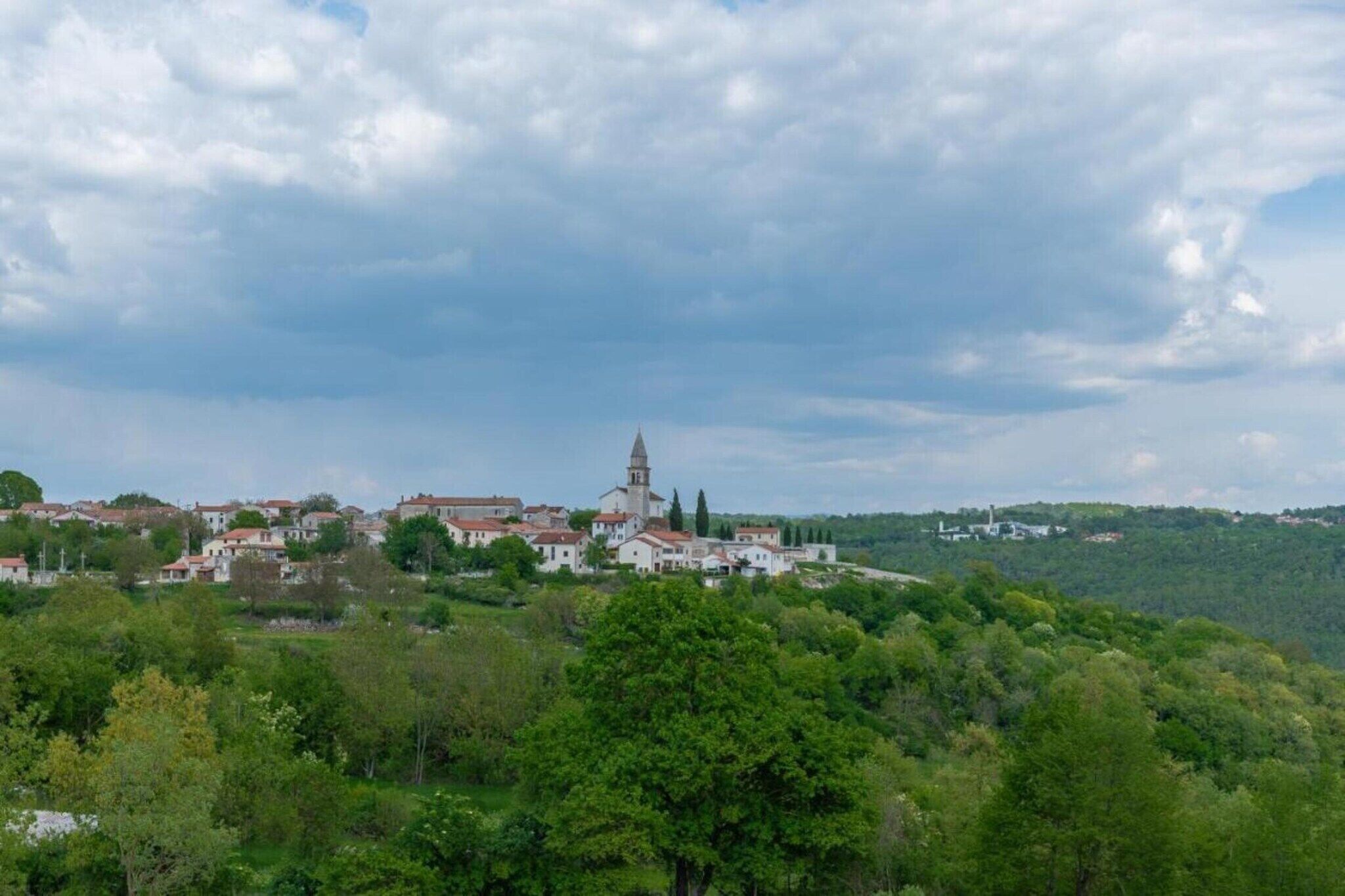 A town with a prominent church on a hill, surrounded by greenery and residential buildings.