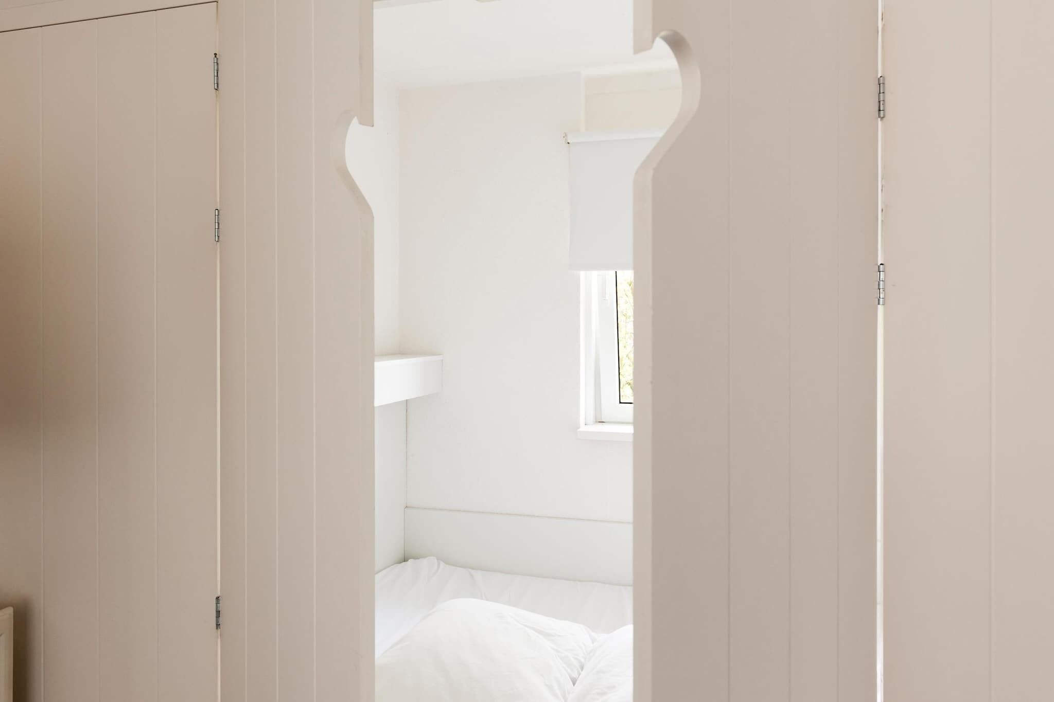 A bedroom with a bed, a window, and a wardrobe.