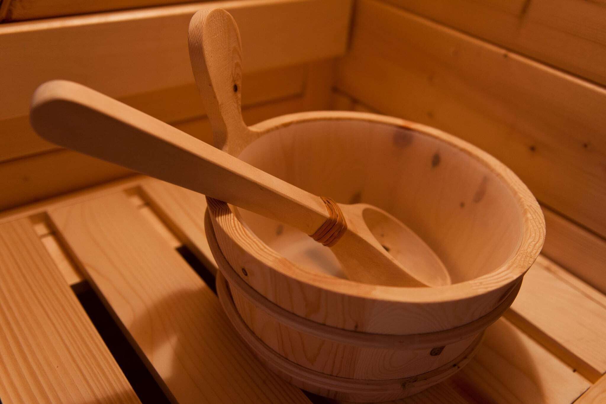 A wooden bowl with a spoon inside, placed on a wooden surface.