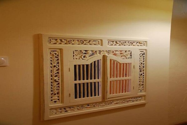 Une fenêtre murale ornée de motifs décoratifs blancs complexes et dotée de deux séries de barreaux verticaux.