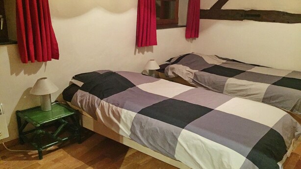 Una camera da letto con due letti, un comodino, una lampada e una finestra con tende.