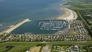 An aerial view of a coastal area with a marina, residential housing, and a beach. - Stylish Marina Loft w/Balcony (Kamperland)