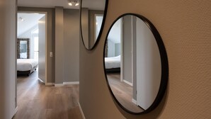 A hotel corridor with a mirrored wall, wooden flooring, and a bed with a patterned headboard in the background. - Stylish Marina Loft w/Balcony (Kamperland)