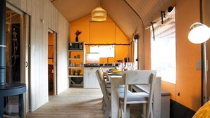 Un ambiente accogliente con un tavolo da pranzo in legno, sedie, un angolo cottura con forno a microonde e un'ampia finestra che permette l'illuminazione naturale.