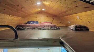 A small, wooden-paneled room with a bed and a sleeping dog.