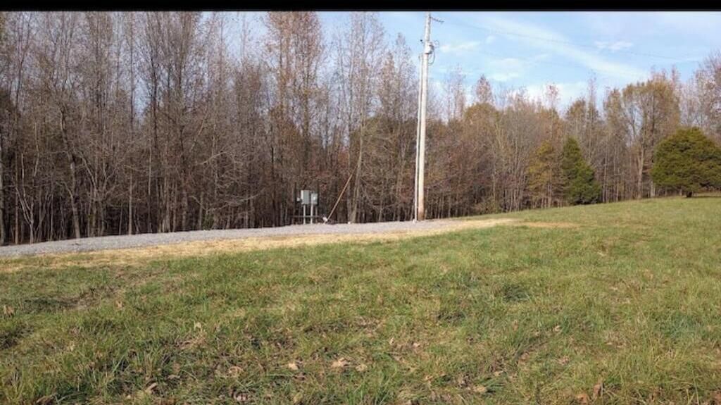 A grassy field with a utility pole and a sign in the distance.