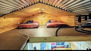 Una piccola camera mansardata con due letti, un soffitto spiovente in legno e un velux.